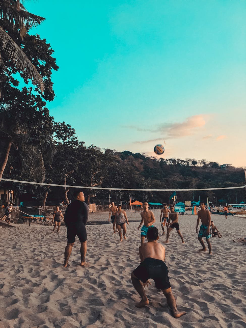 group of people playing beach volleyball on shore